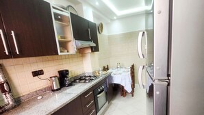 Une cuisine avec des meubles de rangement en bois foncé, une cuisinière à gaz, une machine à café et une table à manger avec des chaises.
