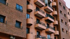 Un immeuble à plusieurs étages, doté de balcons, de fenêtres rectangulaires et d’une façade en briques.