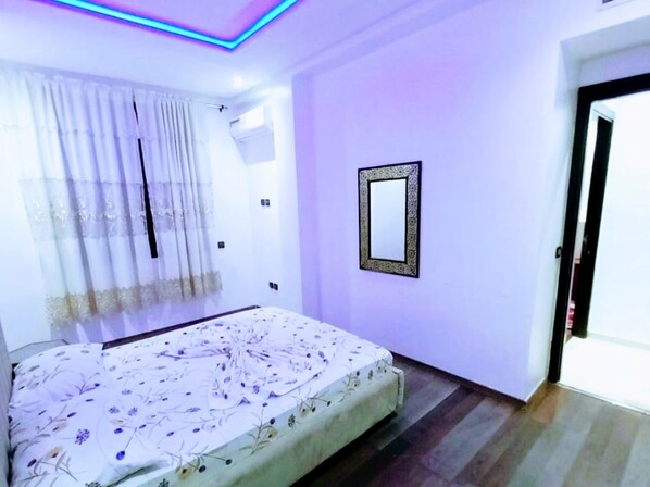A bedroom with a bed, a mirror, and a door.
