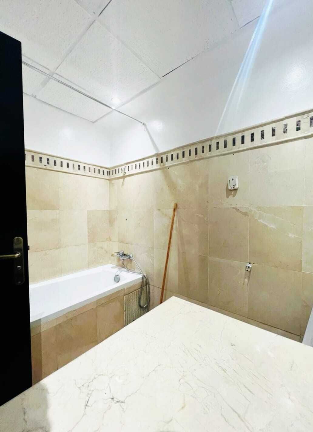 Un baño con bañera, ducha y encimera de mármol.