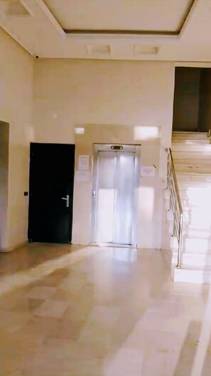 Ein Flur mit geschlossener Tür, einem Aufzug und einer Treppe.