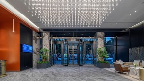 A hotel lobby with a marble floor, a revolving door, and a seating area with a coffee table. - Shangheng Grand Hotel Panzhihua (Panzhihua)