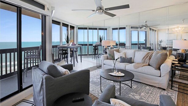 Un vaste espace de vie avec un balcon donnant sur la mer, aménagé avec des canapés et une table basse.