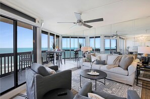 A spacious living area with a balcony overlooking the sea, furnished with sofas and a coffee table.