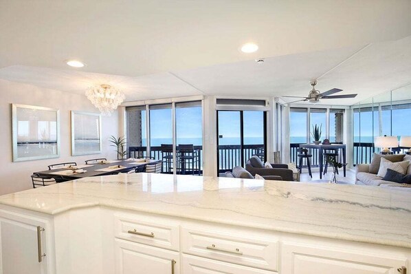 A spacious kitchen with a large island, dining area, and a balcony with a view.
