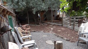 Un área de estar al aire libre de estilo rústico con sillas de plástico y una cerca de madera.