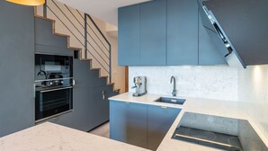 A modern kitchen with a built-in oven, a coffee machine, and a sink.