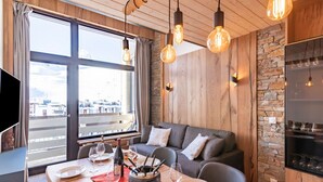 A modern dining area with a wooden table set for a meal, a sofa, and a stone wall.