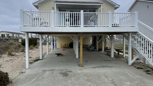 A two-story house with a balcony and a covered patio area. - FENCED IN 2nd Row 2 the sea❤️ Shibumi, beach chairs, and linens included. (Surf City)