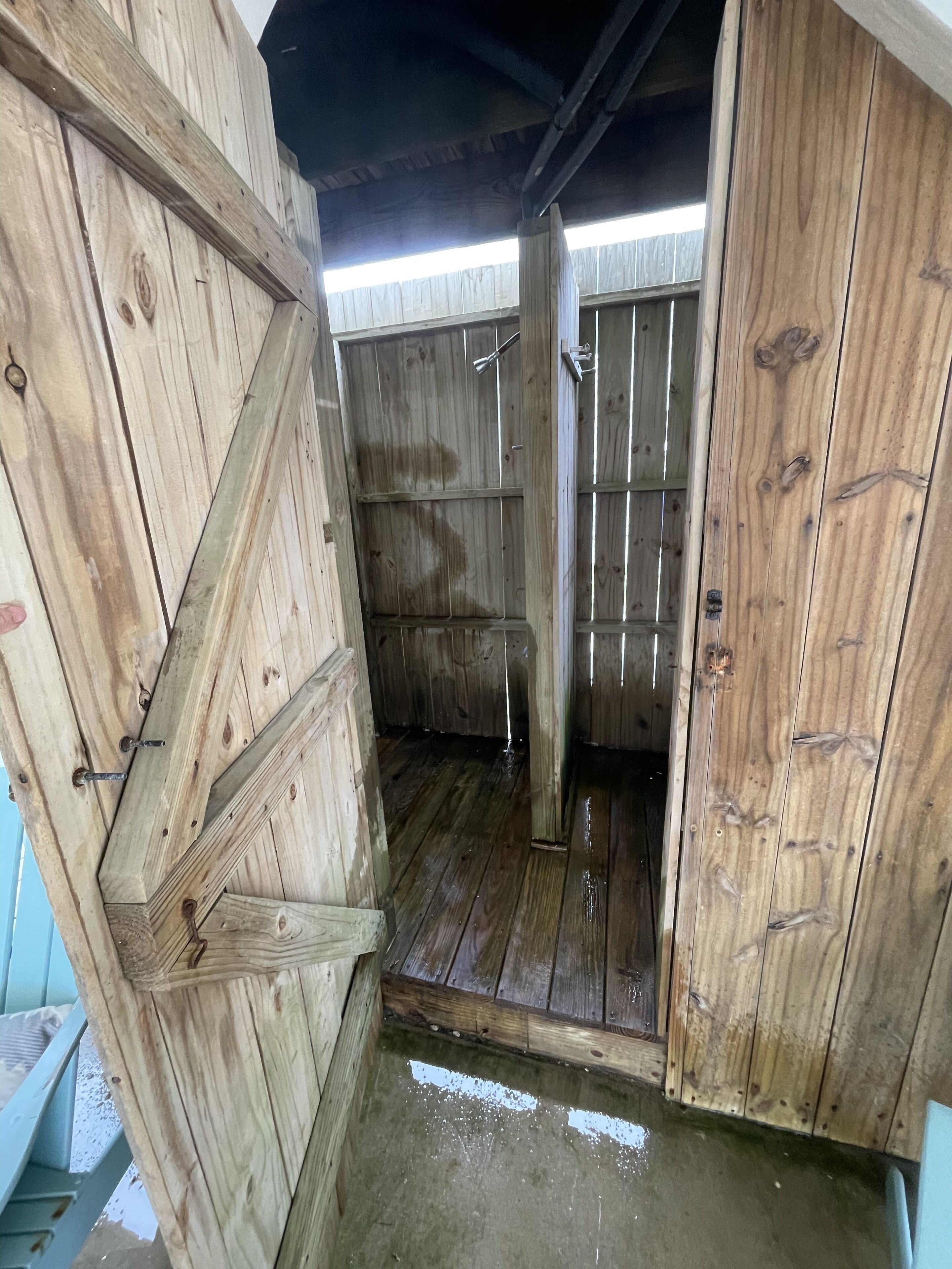 A wooden stable with a metal door, a metal latch, and a metal handle.