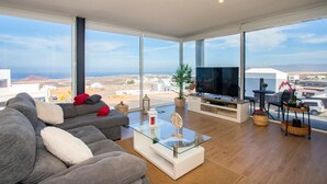 Un salon moderne doté d’un grand téléviseur, de sièges confortables et offrant une vue sur le paysage.