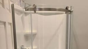 A glass-enclosed shower stall with a door, a towel rack, and a small shelf. - Stylish 1 bedroom studio with kitchenette (Jackson)