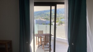 Ein Zimmer mit einem Bett, einem Tisch mit Stühlen und Blick auf einen Balkon mit Tisch und Stühlen.