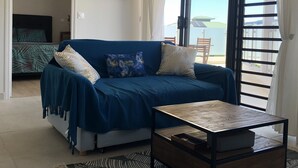 Ein Wohnzimmer mit einem blauen Sofa, einem Holztisch und einem Bild an der Wand.