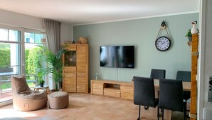 Un salon moderne avec un téléviseur, des meubles en bois et une grande fenêtre.