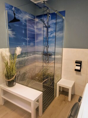 A modern bathroom with a glass shower enclosure, a bench, and a small table. - Modern vacation apartment with terrace, sauna and central location in Zingst - (Zingst)