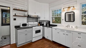 Une cuisine moderne avec des meubles blancs, un four à micro-ondes, une cuisinière et un évier.