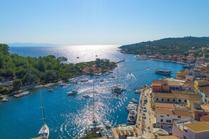 Un pueblo costero con barcos amarrados a lo largo de la marina, rodeado de edificios y vegetación.