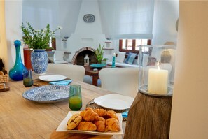 Desayuno con cruasanes, un plato de galletas, un vaso de jugo verde y una vela sobre una mesa de madera.