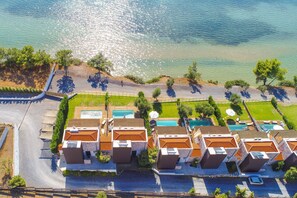 Eine Vogelperspektive eines Küstenhotels mit mehreren Gebäuden, einem Poolbereich und einem Strand.
