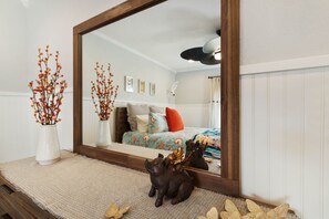 A bedroom with a large mirror, a bed with a colorful bedspread, and decorative items on the nightstand.