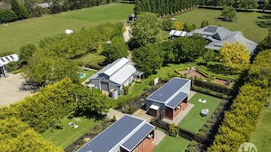 Il s’agit d’une vaste propriété comprenant plusieurs bâtiments, notamment une maison principale dotée d’un grand garage et d’une dépendance plus petite attenante. La propriété est entourée de pelouses bien entretenues et d’une variété d’arbres.