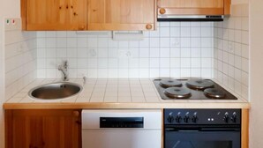 Une cuisine dotée de meubles en bois, d’un évier en acier inoxydable, d’un lave-vaisselle, d’une cuisinière et d’un four.