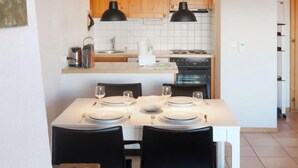 Une cuisine compacte avec des meubles en bois, un plan de travail blanc et un coin repas aménagé pour quatre personnes.