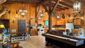 A rustic cabin interior with wooden walls, a dining area, kitchen, and a pool table. - Big Sam Hangout!! 4 bed 3.5 bath South End with rear privacy & Hot Tub (Brookeland)