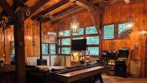 A cozy room with a pool table, wooden walls, large windows, and a ceiling fan. - Big Sam Hangout!! 4 bed 3.5 bath South End with rear privacy & Hot Tub (Brookeland)
