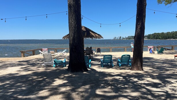 A beach with chairs, a thatched umbrella, and a wooden railing. - Big Sam Hangout!! 4 bed 3.5 bath South End with rear privacy & Hot Tub (Brookeland)