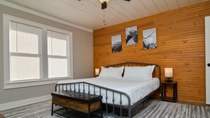 A bedroom with a bed, a bench, a ceiling fan, and wooden paneling on the walls.