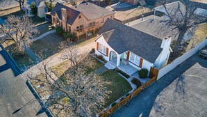 An aerial view of a residential area with houses, a driveway, and a fenced yard.