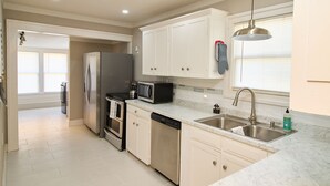 A modern kitchen with white cabinets, stainless steel appliances, a dishwasher, and a double sink.