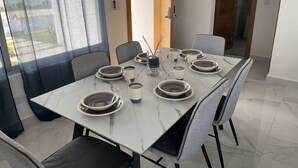 Mesa posta com pratos, tigelas e xícaras, rodeada por cadeiras.