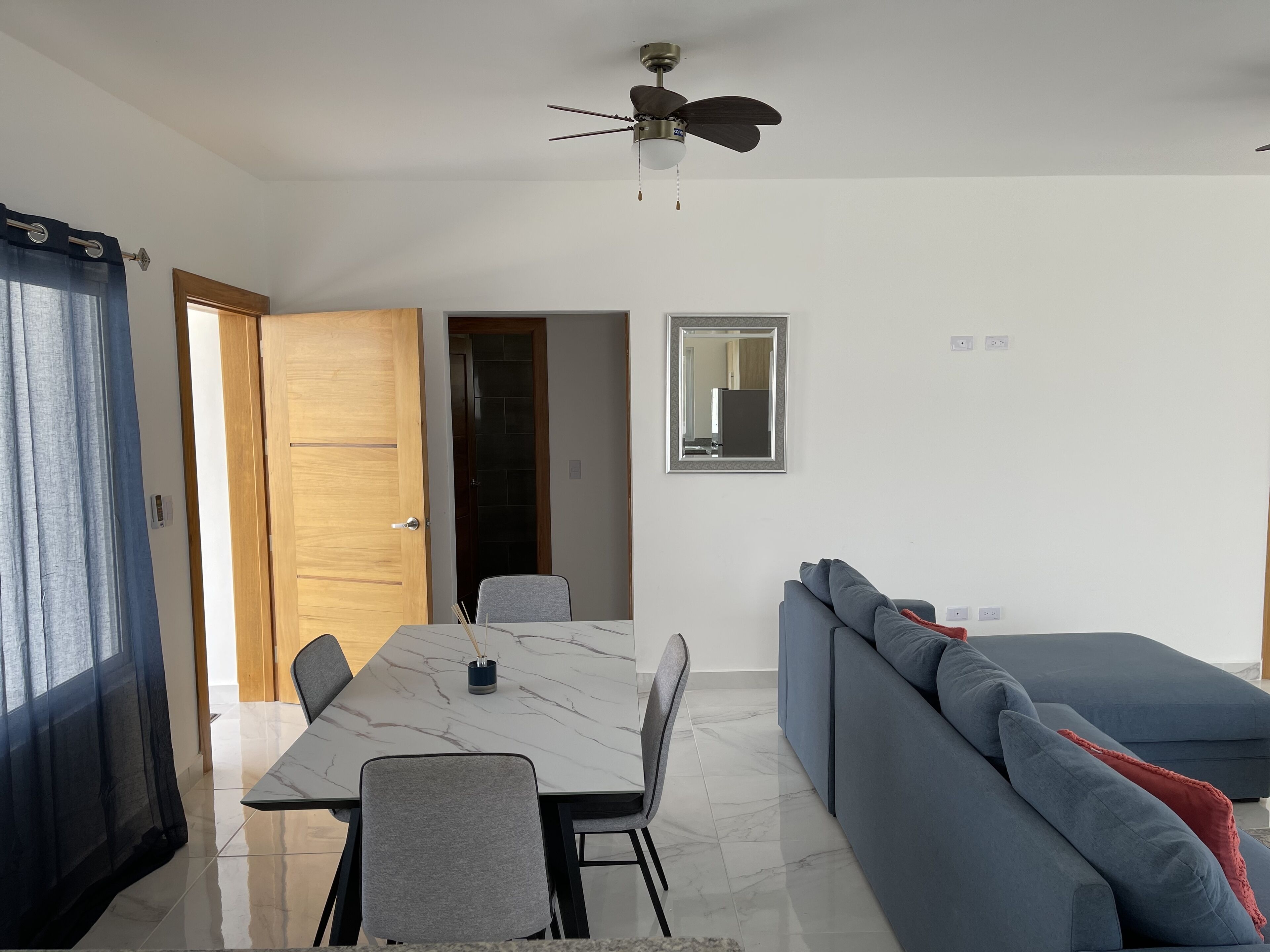 Ein modernes Wohnzimmer mit Esstisch, einer Couch und einem Deckenventilator.