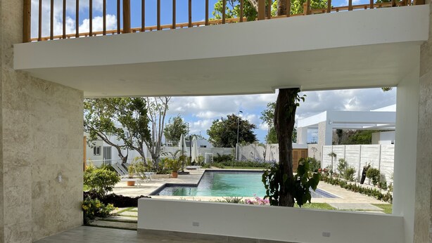 Quarto vazio com vista para uma piscina, móveis de exterior e um deck de madeira.