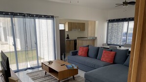 Uma sala de estar moderna com um sofá azul, uma mesa de centro de madeira e uma televisão.