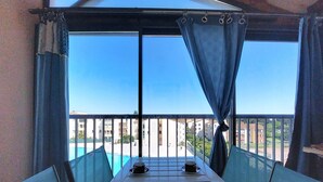 A balcony with a table set for two, a view of buildings, and a clear sky. - Le Lagon Bleu by Interhome (Fréjus)