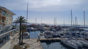 A marina with boats docked, a building with balconies, and a clear sky. - Le Lagon Bleu by Interhome (Fréjus)