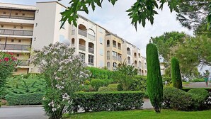 A multi-story residential building with balconies, surrounded by well-maintained gardens and trees. - Le Lagon Bleu by Interhome (Fréjus)