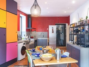 Cocina moderna con comedor, que incluye una isla grande, lavadora y diversos electrodomésticos.