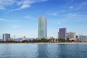 Un paysage urbain côtier avec de hauts immeubles, une plage et un ciel dégagé.