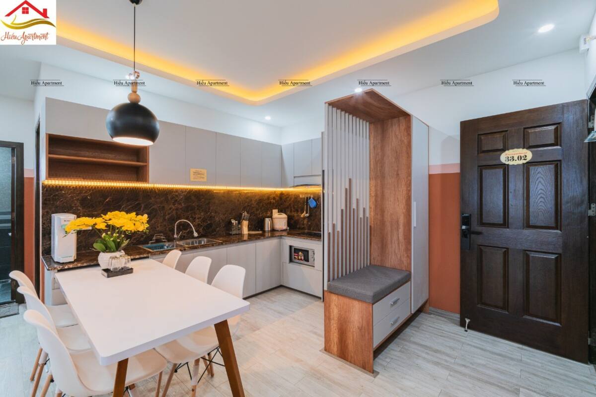 A modern kitchen with a dining area, a built-in bench, and a wooden door with a sign.