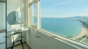A room with a large window overlooking a beach and cityscape. - Tony Luxury Apartment - Venue Stay (Nha Trang)