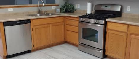 A kitchen with wooden cabinets, a stainless steel dishwasher, a stove, and a microwave.