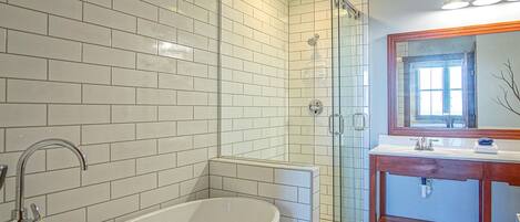 A modern bathroom with a freestanding bathtub, a glass-enclosed shower, and a vanity with a mirror.