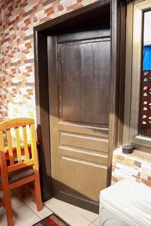 Cozy seating area with a chair and kitchenette, featuring a mosaic tile wall and tiled floor.