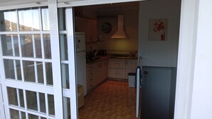 Kompakti keittiö, jossa on jääkaappi, pesuallas ja kaapit.
