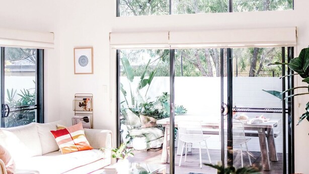 A spacious living area with a large wooden table, a sofa, and a dining table. There are large windows providing natural light and views of greenery outside. - The Villa | Margaret River (Margaret River)